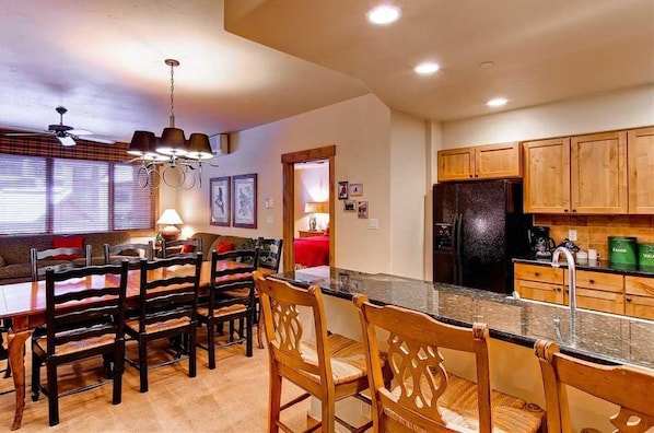 A spacious kitchen with wooden cabinets, a granite countertop, and a dining area with wooden chairs and a table.