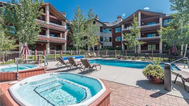A hotel with a swimming pool, hot tubs, and lounge chairs. - 3304 Champagne Lodge, Trappeur's Crossing Apartment 2 (Steamboat Springs)