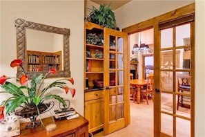 Um quarto com uma estante de madeira, um espelho e um espaço de jantar com mesa e cadeiras.