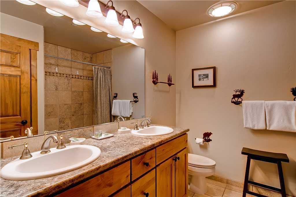 A bathroom with two sinks, a toilet, a shower, and a vanity with a mirror.