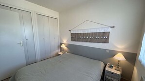 Een slaapkamer met een bed, twee nachtkastjes, een kledingkast en een wandgordijn.