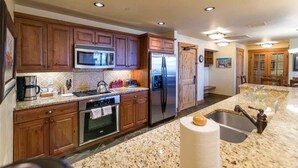 A kitchen with wooden cabinets, stainless steel appliances, granite countertops, and a large island with a sink. - 5101 Emerald Lodge, Trappeur's Crossing Apartment 3 (Steamboat Springs)