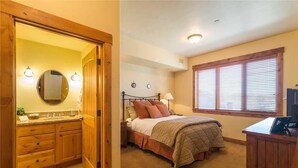 A bedroom with a bed, bedside table, lamp, and a wooden desk. - 5101 Emerald Lodge, Trappeur's Crossing Apartment 3 (Steamboat Springs)