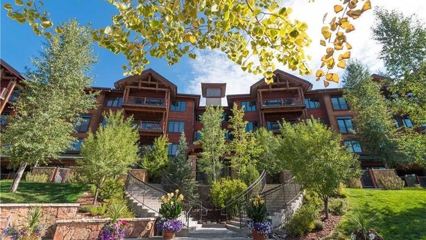 A multi-story building with a symmetrical facade, balconies, and a central entrance. - 5101 Emerald Lodge, Trappeur's Crossing Apartment 3 (Steamboat Springs)
