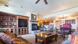A spacious living room with a fireplace, wooden cabinets, and comfortable seating. - 5101 Emerald Lodge, Trappeur's Crossing Apartment 3 (Steamboat Springs)