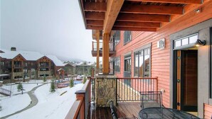 A wooden building with a balcony, stone pillar, and a metal table.