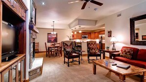 A living room with a television, fireplace, dining area, and kitchen in the background.