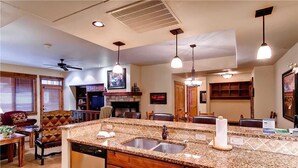 A spacious kitchen with granite countertops, a double sink, and wooden cabinetry.