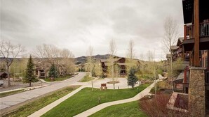A residential area with a well-maintained lawn, pathways, and a mountain in the background. - 5106 Emerald Lodge, Trappeur's Crossing Apartment 5 (Steamboat Springs)