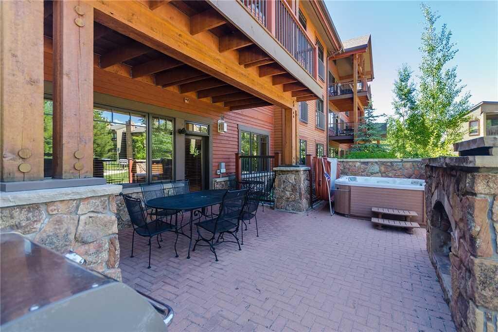 A patio with a table and chairs, a hot tub, and a stone wall.
