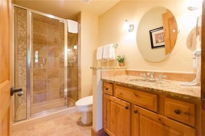 A bathroom with a glass shower enclosure, a toilet, wooden cabinets, and a marble countertop. - 5109 Emerald Lodge, Trappeur's Crossing Apartment 4 (Steamboat Springs)