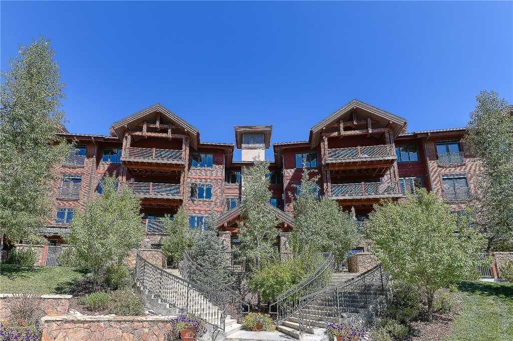 A multi-story building with balconies, a central staircase, and surrounding trees.
