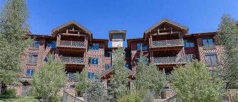 A multi-story building with balconies, a central staircase, and surrounding trees.