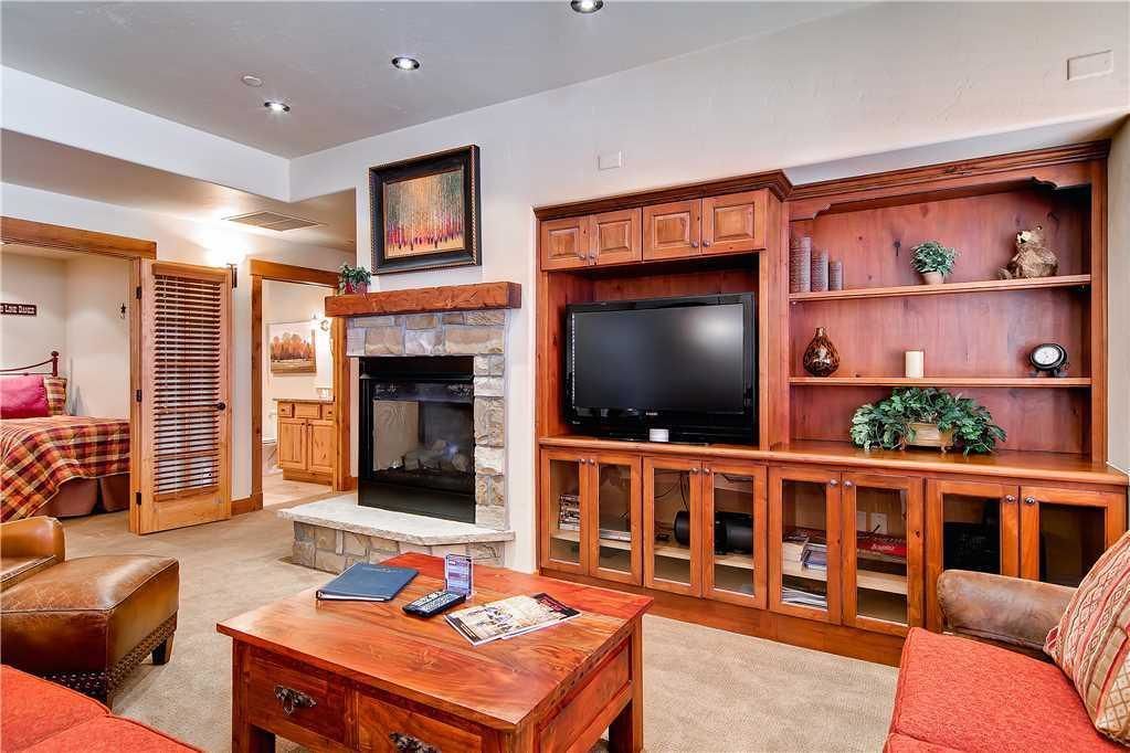 A living room with a fireplace, television, wooden cabinets, and a sofa.
