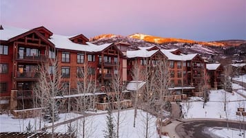 A resort with multiple wooden buildings, a snow-covered landscape, and mountains in the background.
