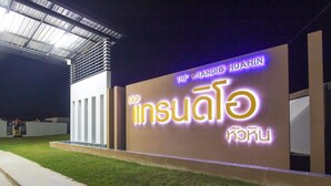 A building with a large illuminated sign reading "The Grandio Huahin" and "insulo" in another script. - Baan Chom Chan Pool Villa (Hua Hin)