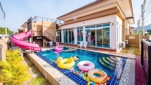 A swimming pool with a slide, inflatable toys, and a building labeled 'CHOMCHAN'. - Baan Chom Chan Pool Villa (Hua Hin)