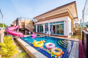 Une piscine avec un toboggan, des jeux gonflables et un bâtiment portant l’inscription « CHOMCHAN ».