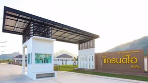 A modern building with a covered entrance and a sign indicating 'The Grandio Huahin'. - Baan Chom Chan Pool Villa (Hua Hin)