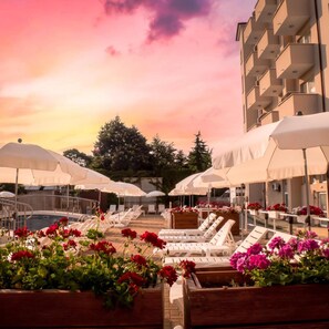 A poolside area with lounge chairs and umbrellas, surrounded by flower planters. - Hotel Aurora - All Inclusive (Varna)