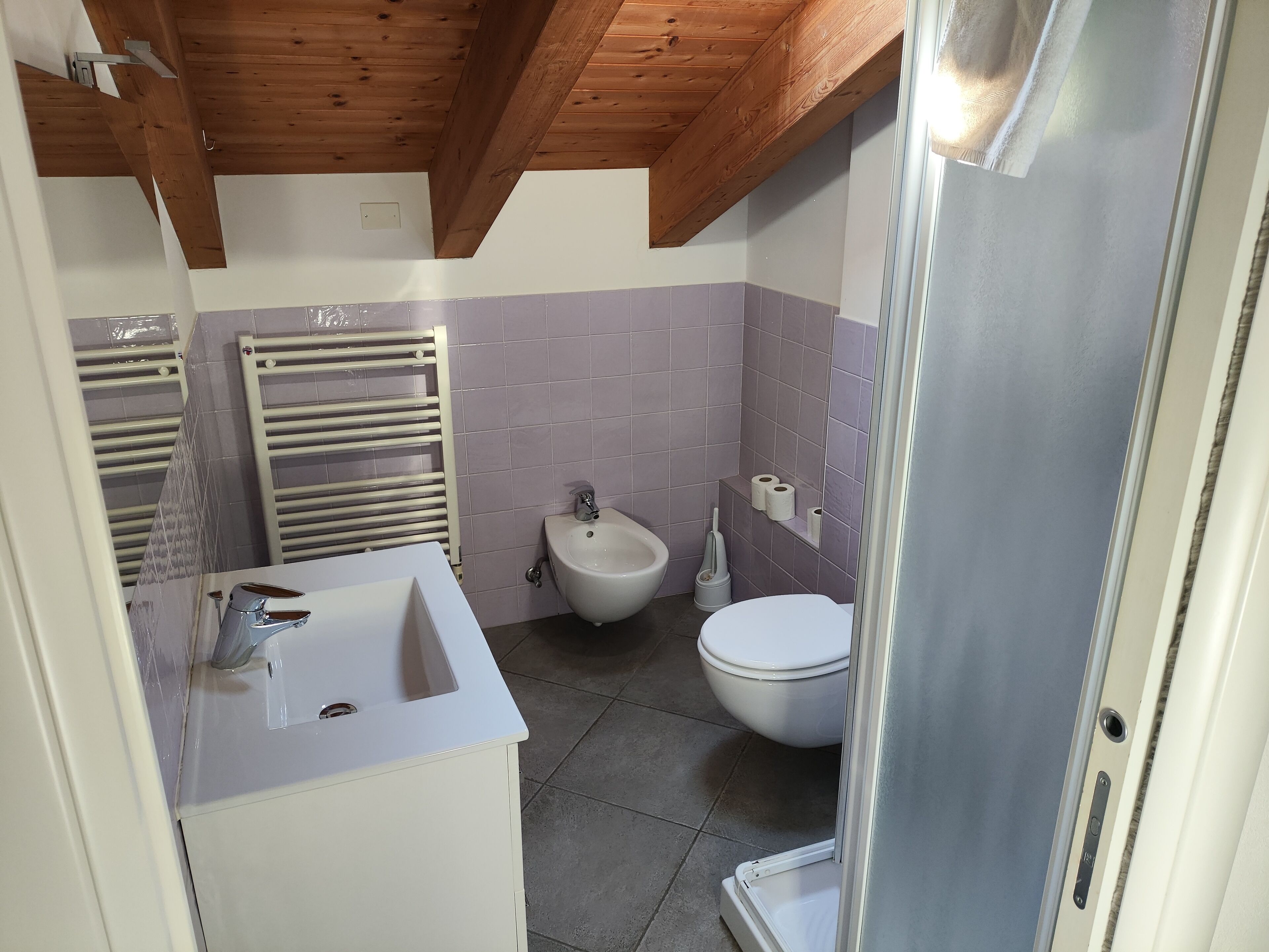 Et badeværelse med vask, bidet, toilet og en brusevæg.