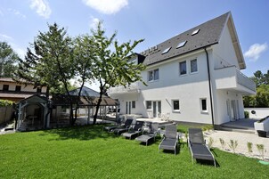 A modern two-story house with a patio area featuring outdoor seating and a small gazebo.