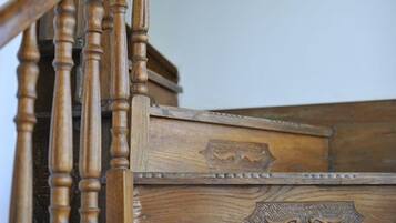 Una escalera de madera con detalles tallados y un cofre de madera al pie.