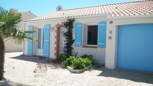A two-story house with blue shutters, a tiled roof, and a gravel driveway. - House near pond, enclosed garden, 2 bedrooms (Bretignolles-sur-Mer)
