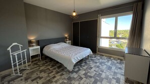 A bedroom with a bed, bedside lamps, a window with a view, and a hanging light fixture. - Beautiful apartment with parking near the beach, 2 rooms, 4 people (Saint-Jean-de-Monts)