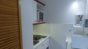 A compact kitchen with a washing machine, a microwave, and a small sink. - 2-room apt closed terrace near beach (Saint-Hilaire-de-Riez)