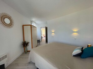 Quarto com cama grande, espelho e duas luzes na parede.