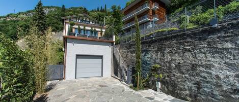 Un edificio moderno con entrada empedrada en piedra, garaje y balcón con vistas a un terreno rocoso.
