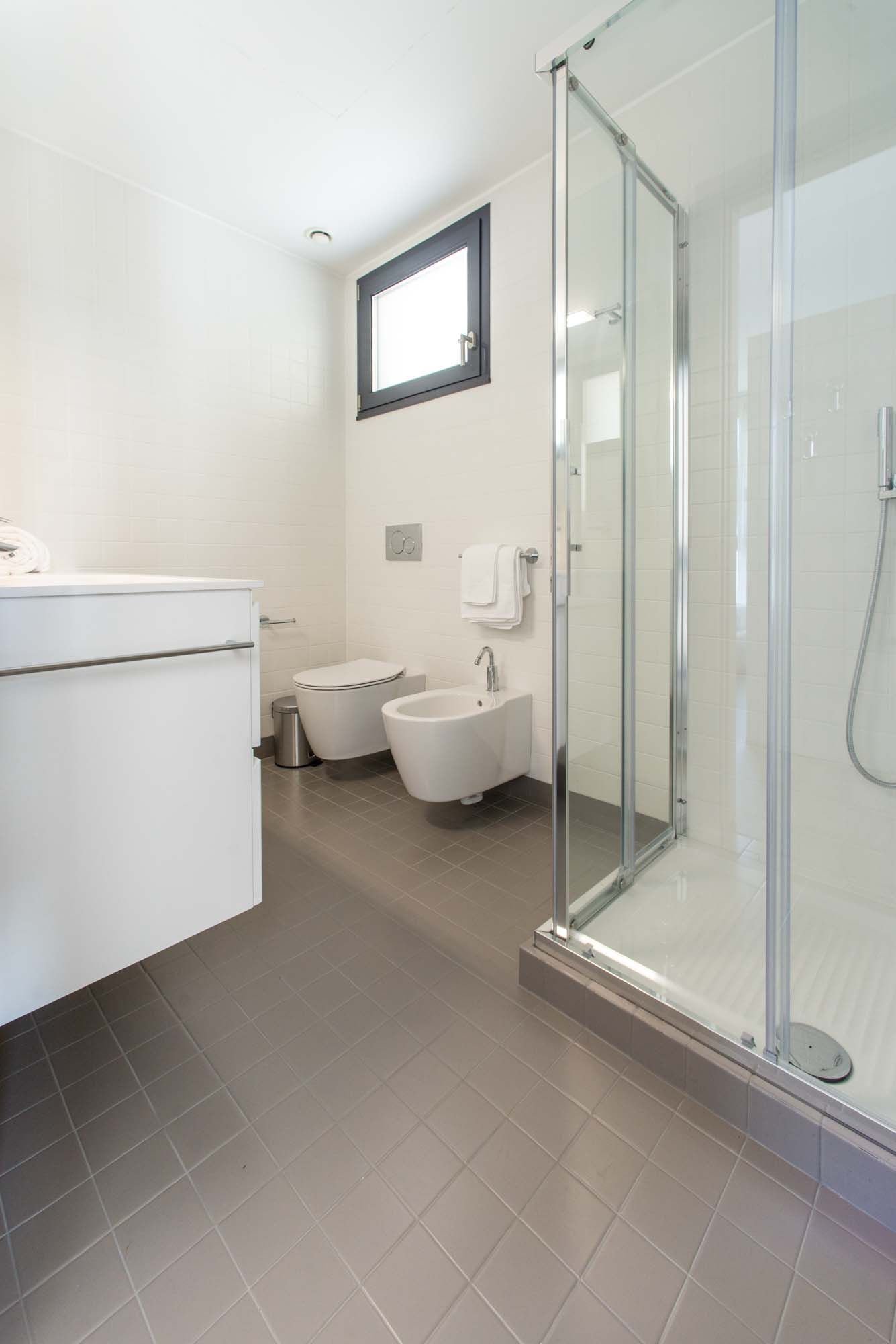 Een moderne badkamer met een douchecabine van glas, toilet, bidet en wastafel.