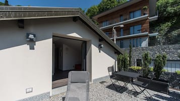 A modern building with a sloped roof, a patio with outdoor furniture, and a stone wall.