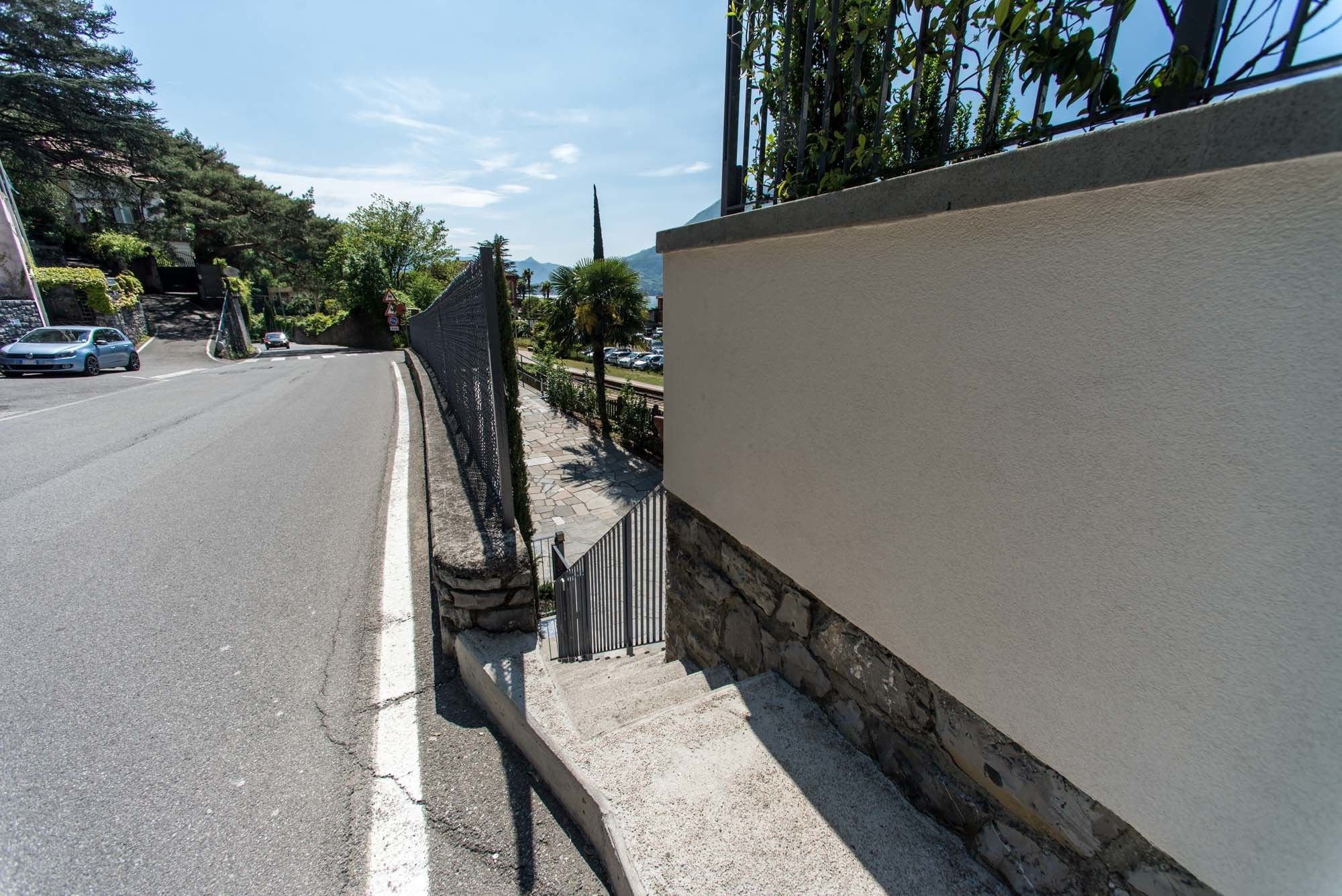 A street with a sidewalk, a stone wall, and a parked car.