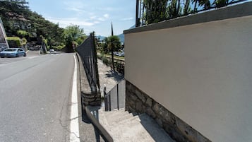 A street with a sidewalk, a stone wall, and a parked car.