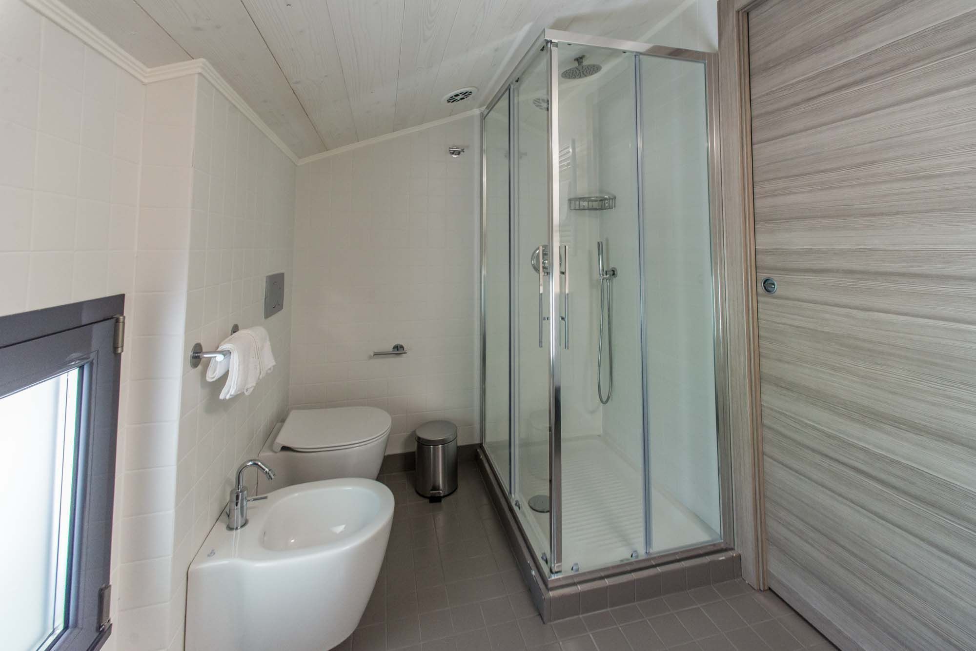 Un baño moderno con ducha envuelta en vidrio, lavamanos blanco y retrete.