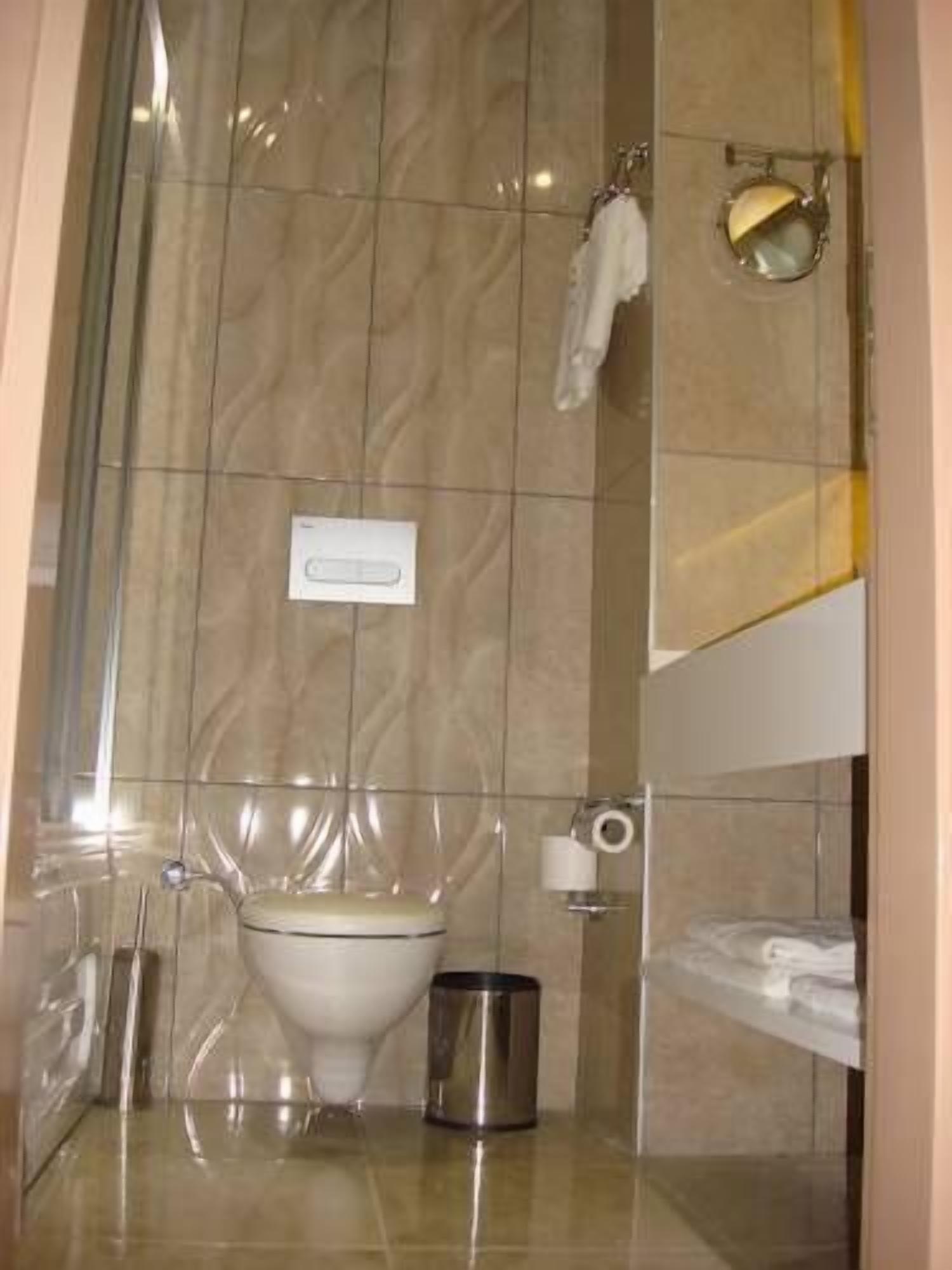Une salle de bain équipée de toilettes, d’une poubelle et d’un porte-serviettes.