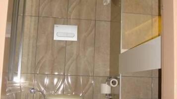 Une salle de bain équipée de toilettes, d’une poubelle et d’un porte-serviettes.