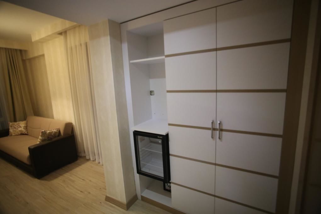 Habitació amb un sofà, un petit televisor amb marc negre i un armari blanc amb línies horitzontals.
