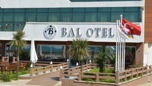 A hotel named "BAL OTEL" with a modern facade, outdoor seating area, and a flag. - Bal Otel (Tirebolu)