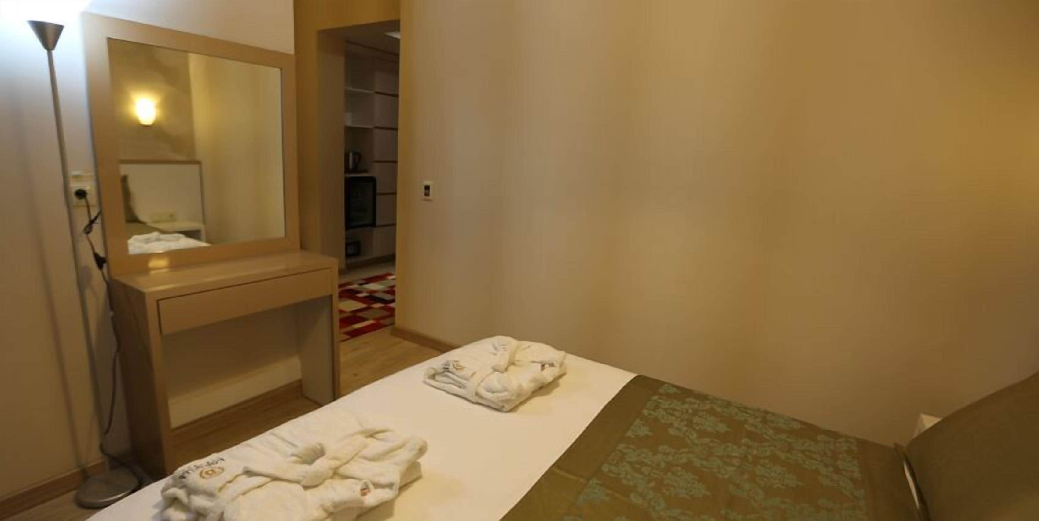 A hotel room with a bed, a bedside table, a mirror, and a wardrobe.