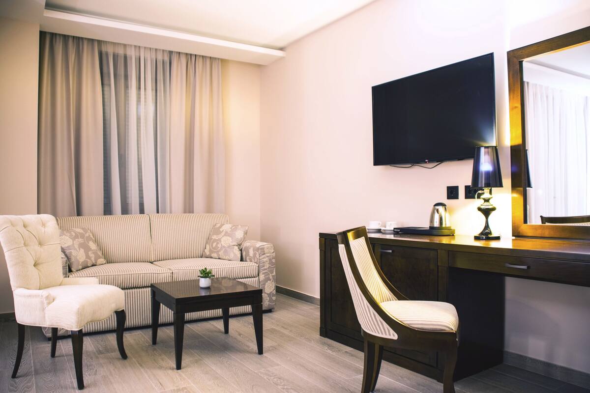 Una sala de estar moderna con un sofá seccional, una mesa de centro, un escritorio con una silla, un televisor de pantalla plana y un espejo grande.