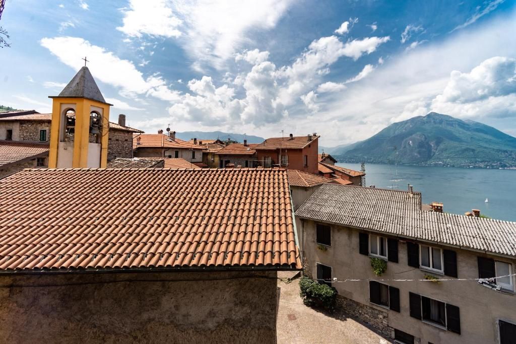 Une ville côtière aux bâtiments aux toits de tuiles rouges, avec un clocher et une montagne en arrière-plan.
