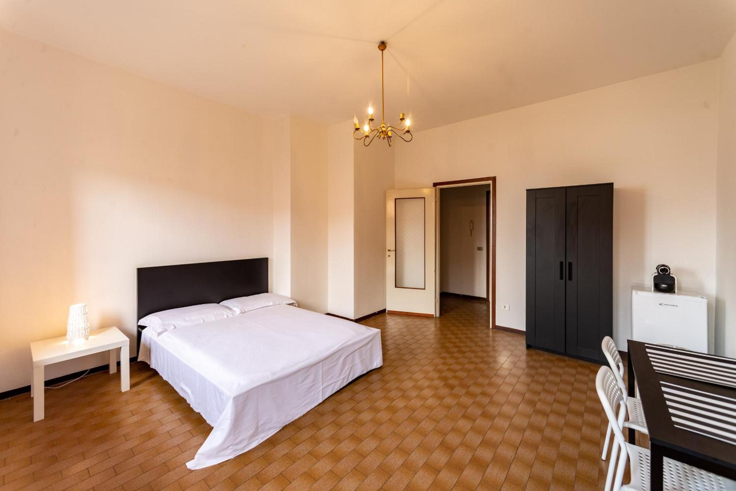 Une chambre d’hôtel comprenant un lit, une table de chevet, une armoire et un bureau avec des chaises.