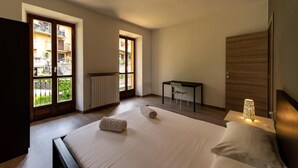 A hotel room with a bed, a desk, a chair, and a view of the outside. - Regolo House (Perledo)