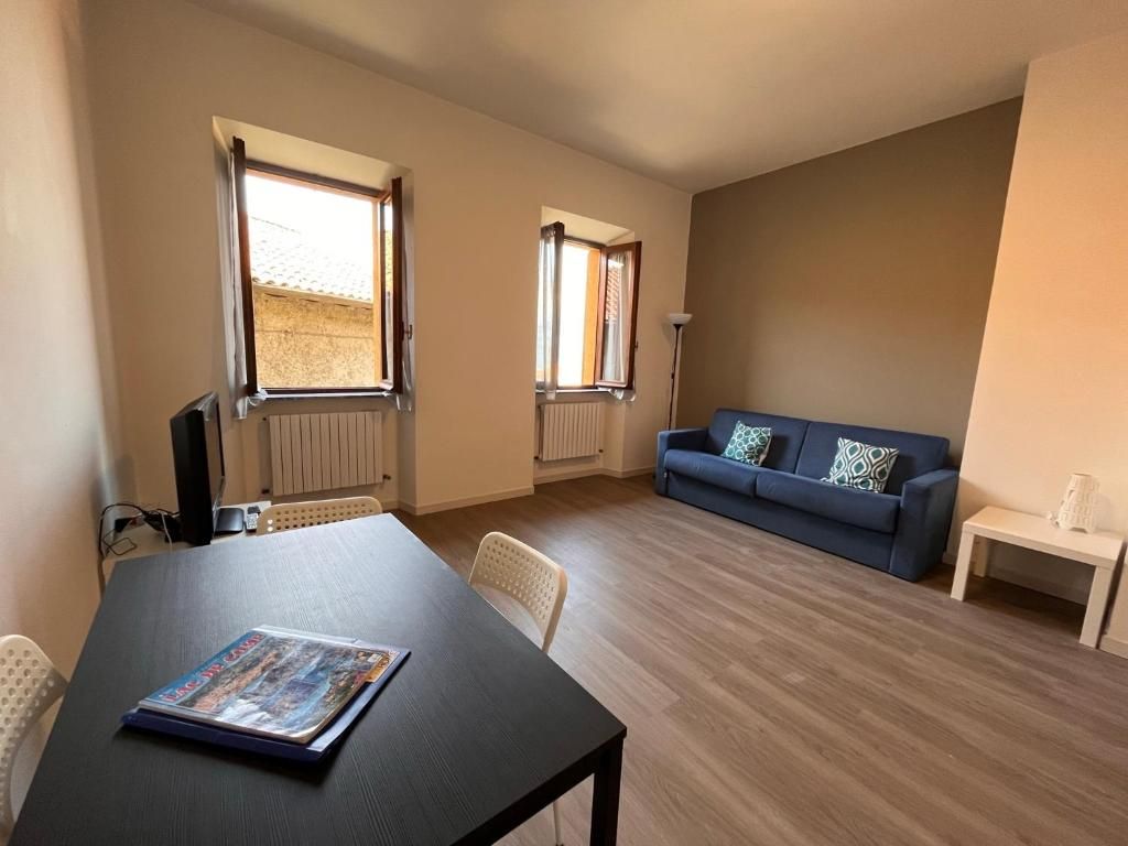 Ein Zimmer mit einem Esstisch, einer Couch und zwei fensterbepflanzten Fenstern.