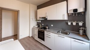 A modern kitchen with white cabinets, a built-in oven, a stainless steel sink, and a wall-mounted heater. - Regolo House (Perledo)