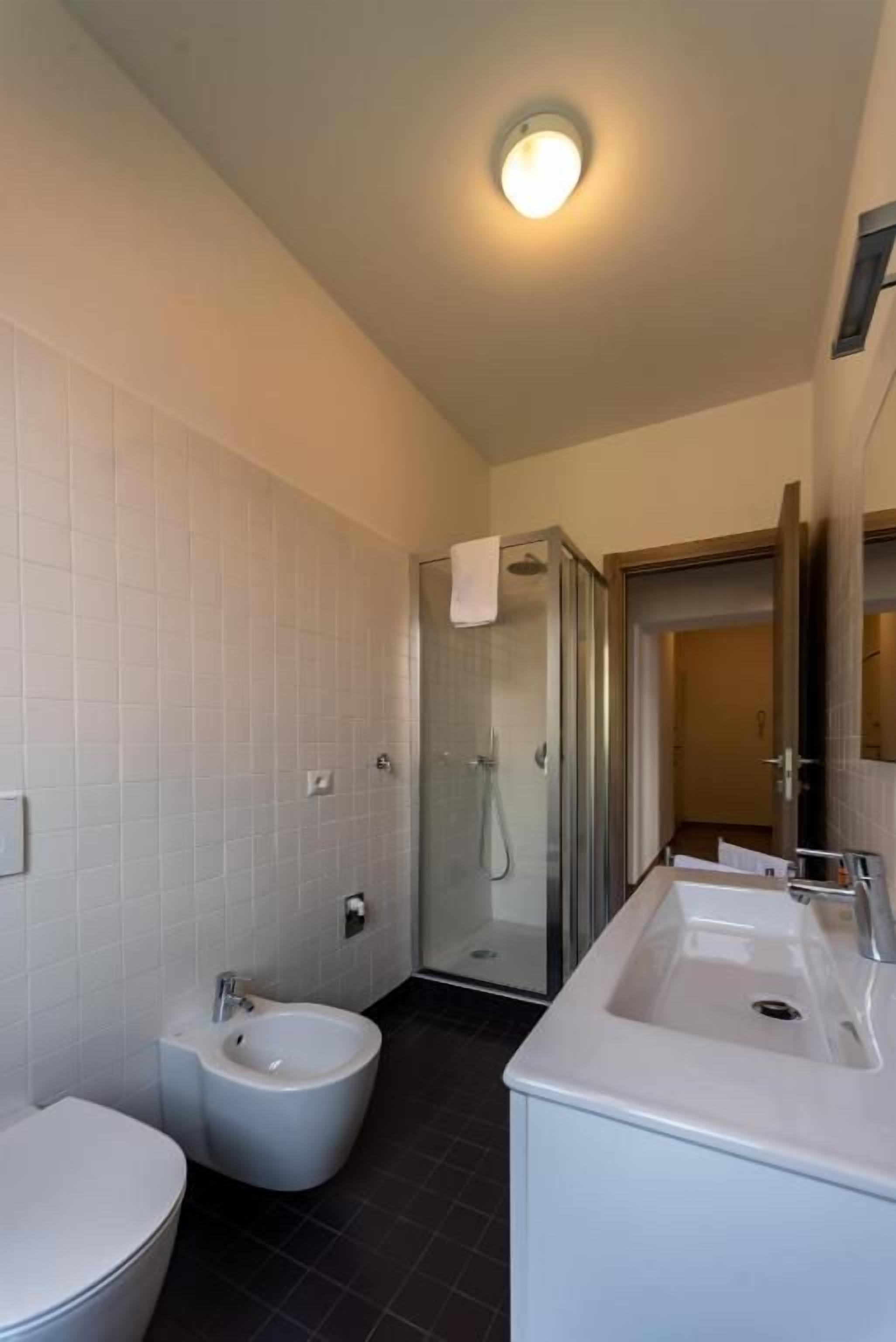Une salle de bain comprenant des toilettes, un bidet et un espace douche.