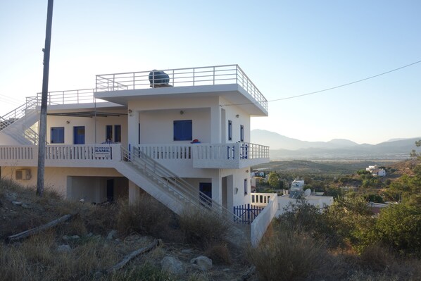 A two-story building with a balcony, a staircase, and a view of the surrounding landscape. - Panoramakamil (Faistos)